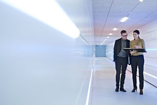 Businesspeople standing in an office corridor looking at a file