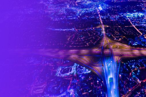 Aerial view of highway cloverleaf and city lights at night