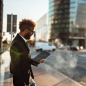 Mature businessman using digital tablet on footpath during sunny day